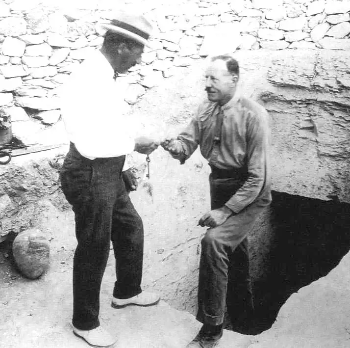 Howard Carter et Lord Carnarvon debout au sommet des marches menant au tombeau de Toutankhamon.